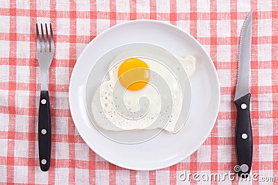 Fried egg in plate with fork and knife on the table