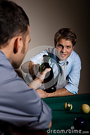Friends clinking beer bottles at snooker table