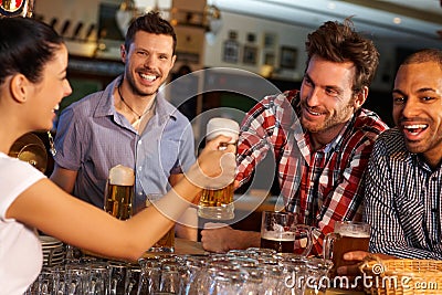 Friends drinking beer at counter in pub