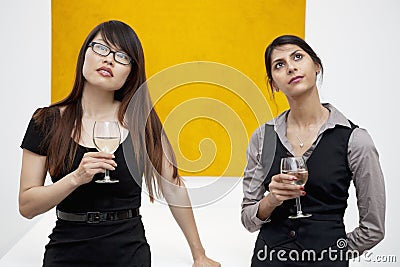 Front view of young females with wine glass looking up in art gallery
