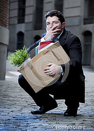 Frustrated business man on street fired carrying cardboard box