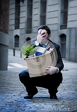 Frustrated business man on street fired carrying cardboard box