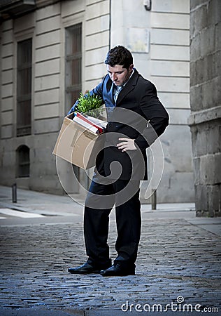 Frustrated business man on street fired carrying cardboard box