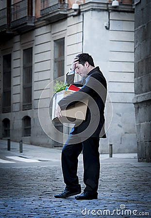 Frustrated business man on street fired carrying cardboard box