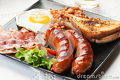 Full English breakfast with bacon, sausage, egg, baked beans and orange juice