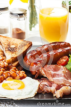 Full English breakfast with bacon, sausage, egg, baked beans and orange juice