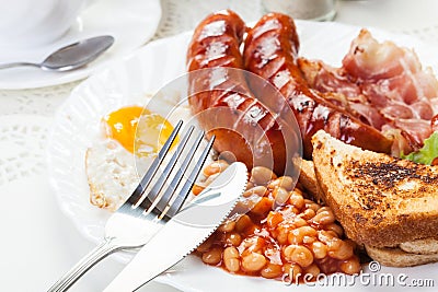 Full English breakfast with bacon, sausage, fried egg and baked