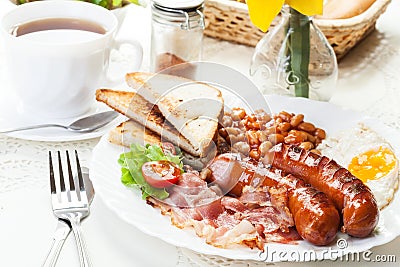 Full English breakfast with bacon, sausage, fried egg and baked