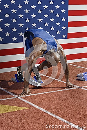 Full length of male athlete ready to race with American flag in background