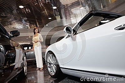 Full-length of smiling woman standing in car showroom
