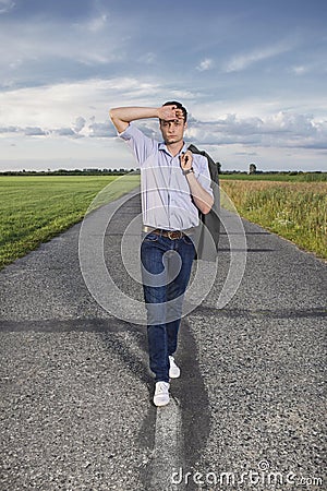 Full length of tired young man walking alone on rural road