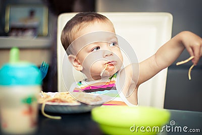 Funny baby boy eating spaghetti