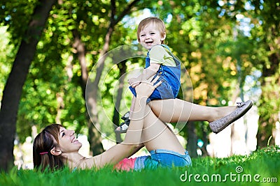 Funny baby with mom in a greenl summer park