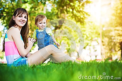 Funny baby with mom in a greenl summer park