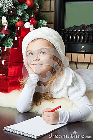 Funny girl in Santa hat writes letter to Santa