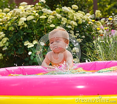 Funny little boy playing with water in baby pool