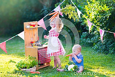 Funny little kids playing with toy kitchen in the garden