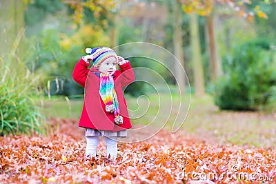 Funny little toddler girl playing in autumn park