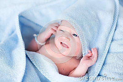 Funny newborn baby covered in blue bath towel