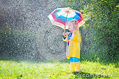 Funny toddler with umbrella playing in the rain