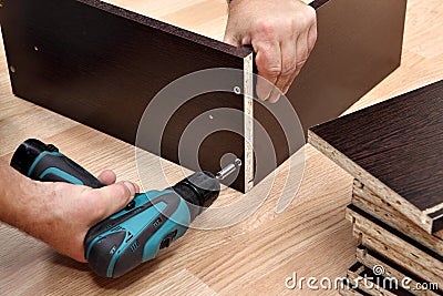 Furniture assembly using a cordless screwdriver, close up.