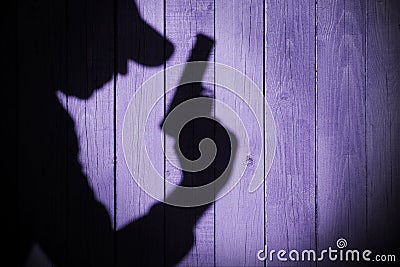 Gangster or investigator or spy silhouette on natural wooden wal