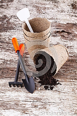 Garden tools (shovel, rake, peat pots ) on old wooden background