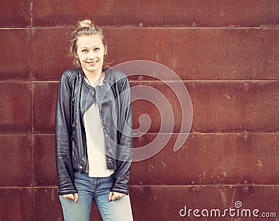 Girl in a black leather jacket posing in a rusty metal wall. Outdoor