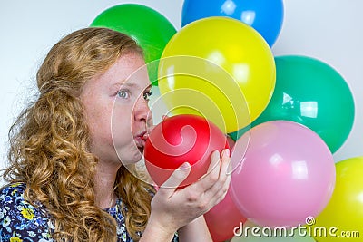 Girl blowing inflating colored balloon