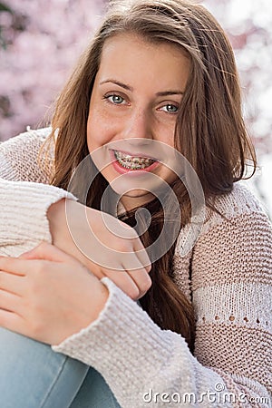 Girl with braces hugging knees in nature