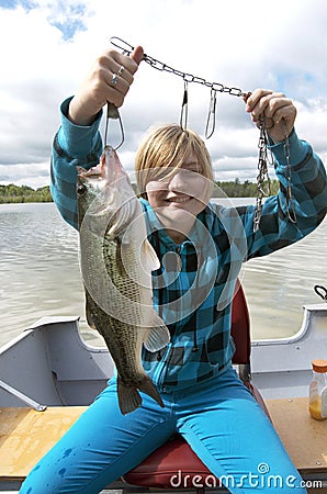 Girl Catching Big Bass In Boat On Lake