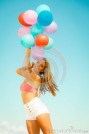 Girl with colorful balloons on beach