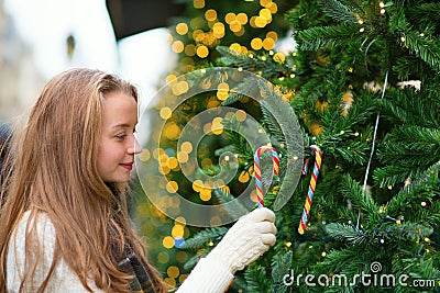 Girl decorating Christmas tree with candies