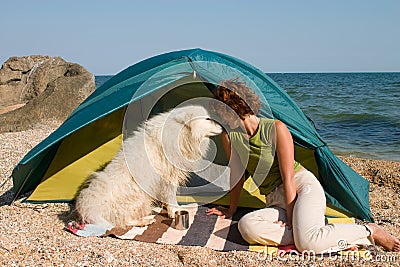 Girl with dog sitting near of a tent