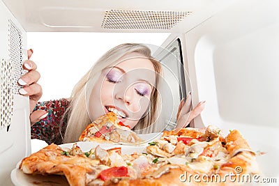 Girl eats pizza out of the microwave