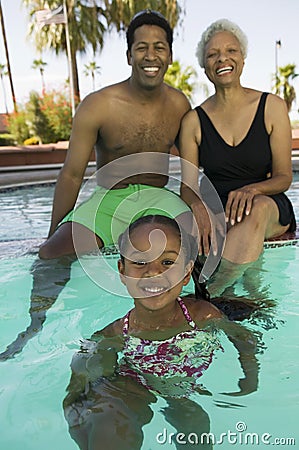 Girl (5-6) with father and grandmother at swimming pool portrait.