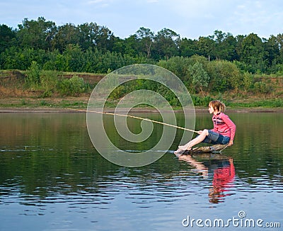 Girl-fisher sits on a log in the middle