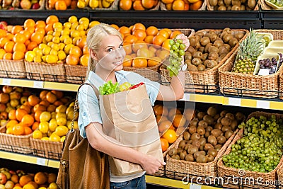 Girl hands bag with fresh vegetables choosing grape