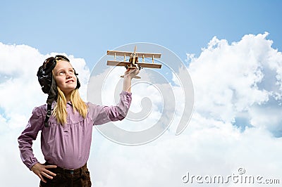 Girl in helmet pilot playing with a toy airplane