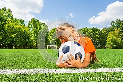 Girl holding close football, smiling and laying