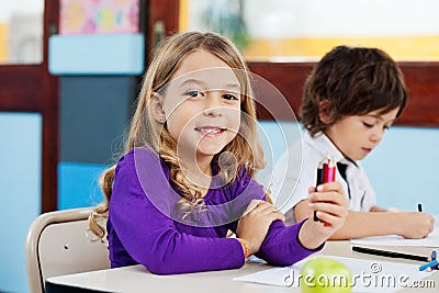 Girl Holding Color Pencils With Friend Drawing In