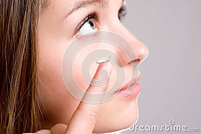 A girl holds a contact lens