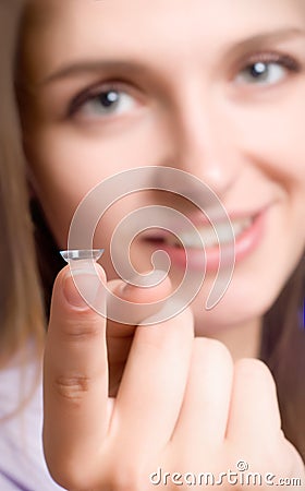 A girl holds a contact lens