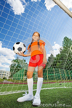 Girl holds football, stands in front of woodwork