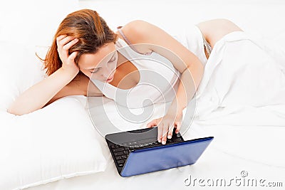 Girl with laptop lying in her bed