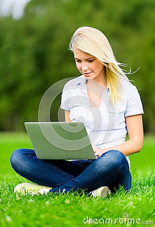 Girl with laptop sitting on the green grass