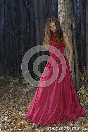Girl leaning against tree in forest