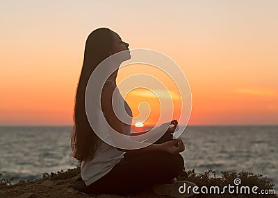 Girl in lotus pose at sunset