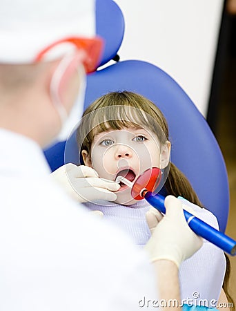 Girl with open mouth receiving dental filling dryi