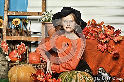 Girl in an orange sweater and hat in Halloween witch